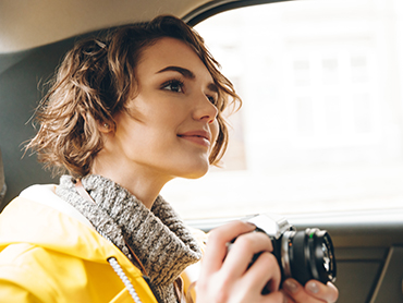 Pretty young lady photographer dressed in raincoat